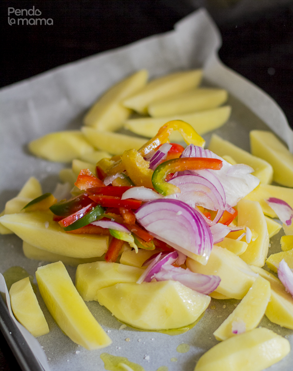 potato wedges, onion slices, red and yellow pepper slices, in an oven pan covered with parchment paper, sprinkled with oil and salt